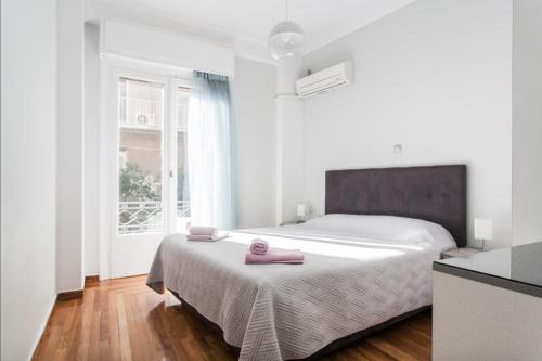 a white bedroom with a bed with pink towels on it at Beautiful Apartment at Plaka in Athens