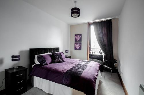 um quarto com uma cama roxa e uma janela em City Centre Orange Apartments Bastille em Aberdeen