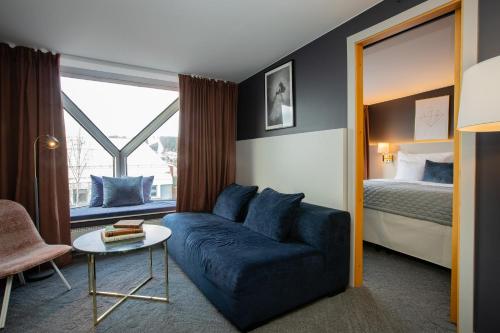 a living room with a blue couch and a bed at Clarion Hotel Grand Östersund in Östersund