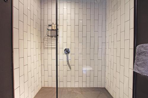 a bathroom with a shower with white tiled walls at Wex apartments in Cape Town