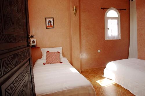 a small bedroom with two beds and a window at Dar Océana in Tamraght Oufella