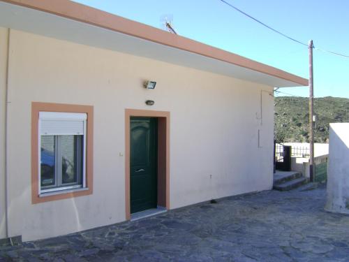 a white building with a green door and a window at Argoules House in Argoulés
