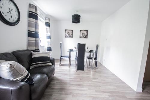 a living room with a couch and a clock on the wall at Orange Town House - Shaw Road, Only 6 Minutes to City Centre in Aberdeen