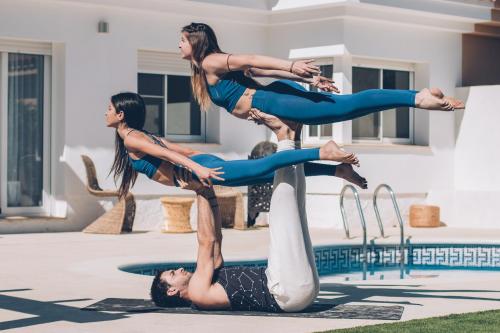 un grupo de tres mujeres haciendo un haz de equilibrio junto a una piscina en Villa Fernweh - Delta de l'Ebre, en Riumar