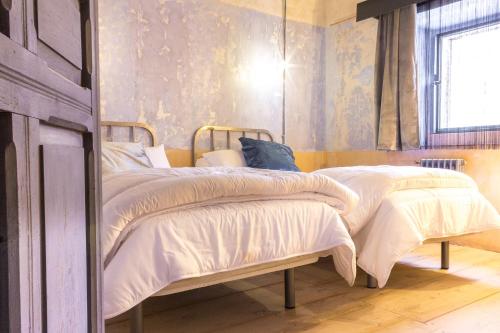 a bedroom with two beds with white sheets and a window at Casa Rural La Abacería in Mino de Medinaceli