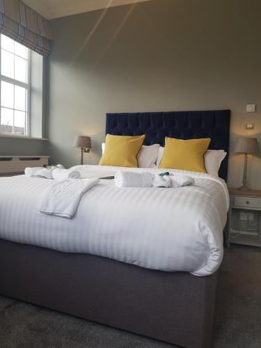 a large white bed with yellow pillows in a bedroom at The Royal Oak in Woodford