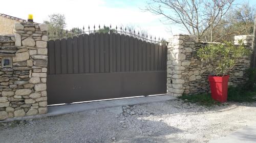 a black gate with a stone fence and a stone wall at Le Mas des Alexandrins in Uzès