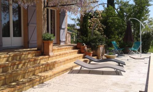 a patio with two benches and chairs on a house at Michèle et Didier Lin in Saint-Laurent-dʼAigouze