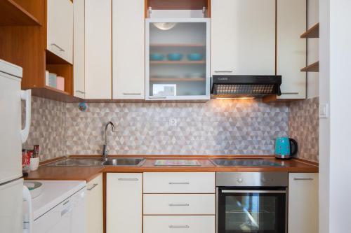 una cocina con armarios blancos y fregadero en Sidro apartment en Split
