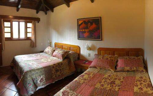 een slaapkamer met 2 bedden en een raam bij Posada De Los Volcanes in Panajachel