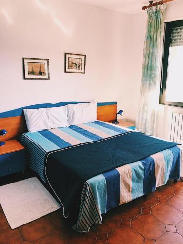 a bedroom with a bed with a blue and striped blanket at B & B Brisa del Mar in Alghero