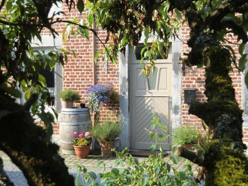 a white door with potted plants on a brick house at B&B Au Coeur de Villers in Villers-Sainte-Gertrude