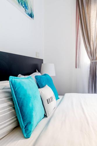 a bed with blue and white pillows on it at AYZ Javier Cabrini - Auto check-in property in Madrid