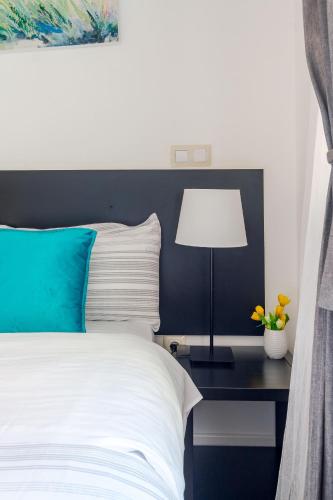 a bed with a blue headboard and a table with a lamp at AYZ Javier Cabrini - Auto check-in property in Madrid