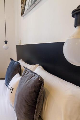 a bed with a black and white headboard and pillows at AYZ Javier Cabrini - Auto check-in property in Madrid