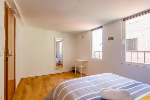 a white bedroom with a bed and two windows at AYZ Javier Cabrini - Auto check-in property in Madrid