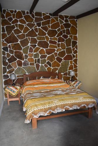 1 dormitorio con 1 cama y pared de piedra en Hostal Wilma, en Toro Toro