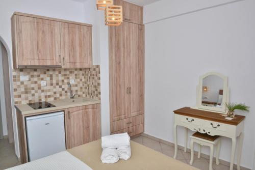 Delfinaki Lionas Boutique Apartments في Lionas: مطبخ بدولاب خشبي ومغسلة ومرآة