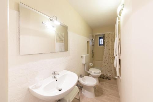 a white bathroom with a sink and a toilet at A casa di Francesca in Ostuni