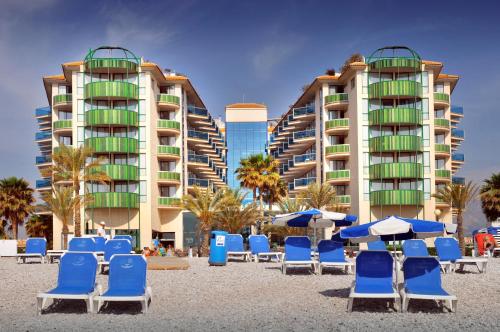 eine Gruppe von Stühlen und Sonnenschirmen an einem Strand mit Gebäuden in der Unterkunft KAKTUS Hotel Kaktus Albir in Albir