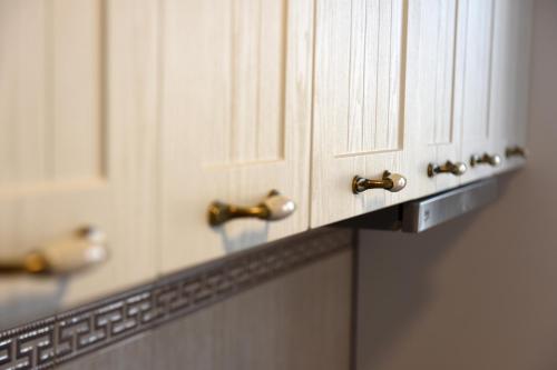 a row of white cabinets with gold handles at Best Apartment Suceava in Suceava