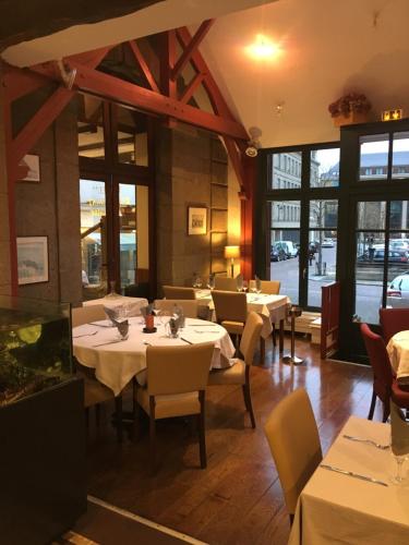 un restaurante con mesas y sillas blancas y ventanas en Hotel Brasserie Armoricaine, en Saint-Malo