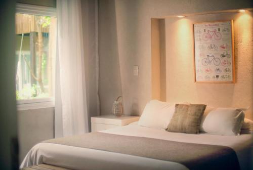 1 dormitorio con 1 cama blanca y ventana a Pleniluni Mar de las Pampas, en Mar de las Pampas
