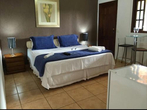 a bedroom with a large bed with blue pillows at Pousada Recanto do Chalé Ltda in Macacos