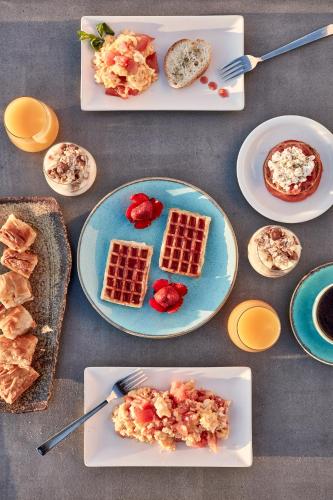 a table topped with plates of waffles and breakfast foods at Elysian Santorini in Oia