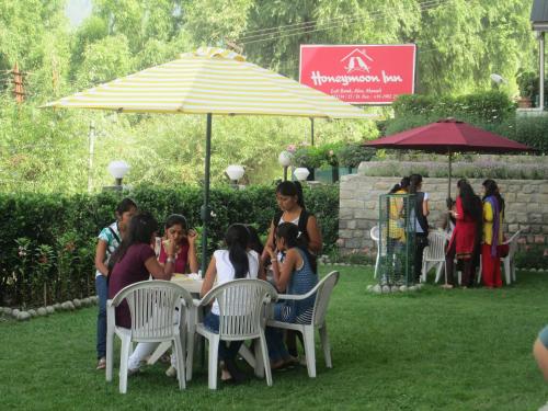 a group of people sitting at a table under an umbrella at Honeymoon Inn Manali in Manāli