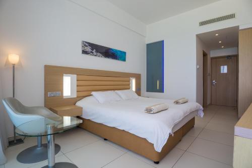 a bedroom with a bed and a desk and a chair at Vrissaki Beach Hotel in Protaras