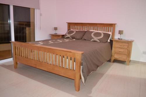 a bedroom with a wooden bed and two night stands at Oceania Bay Village in Pyla