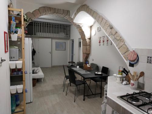 uma cozinha com uma mesa com cadeiras e um arco em A cà du Pellegrin em Carloforte