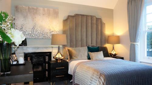 a bedroom with a bed and a desk with two lamps at The Lawn Guest House Gatwick in Horley