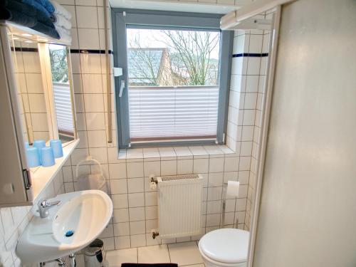 uma casa de banho com um lavatório, um WC e uma janela. em Ferienwohnung Eggeblick em Altenbeken