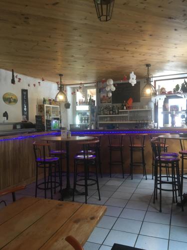 - un bar dans un restaurant avec tabourets de bar violets dans l'établissement Auberge La Caverne, à Laruns
