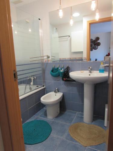 a blue tiled bathroom with a sink and a toilet at Apartamento La Figuereta, Isla Cristina in Isla Cristina
