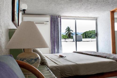 a bedroom with a bed with a lamp and a window at Coral Ixtapa in Ixtapa