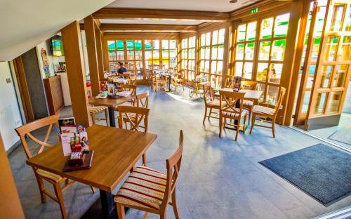 a restaurant with wooden tables and chairs and windows at Guest House Pri Cesarju in Kamnik