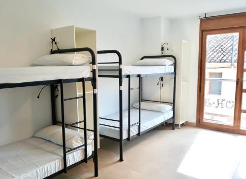 a room with three bunk beds and a window at Hornillos Meeting Point (Pilgrim Hostel) in Hornillos del Camino