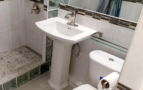 La salle de bains blanche est pourvue d'un lavabo et de toilettes. dans l'établissement Beach One Bedroom Suite A17, à Ocho Rios