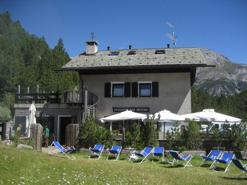 eine Gruppe von Stühlen und Sonnenschirmen vor einem Gebäude in der Unterkunft Chalet Villa Valania in Valdidentro