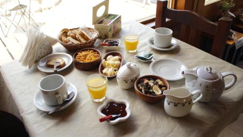 a table topped with cups and plates of breakfast food at Hostería Meliquina in Lago Meliquina