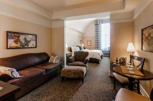 a hotel room with a couch and a bed at Le St-Martin Hotel & Suites in Laval