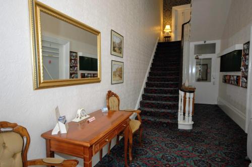 a hallway with a table and a mirror and stairs at The Maynard in Scarborough