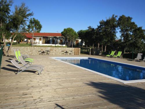 a swimming pool with two lawn chairs and a swimming pool at Casa de Campo Vale do Asno in Altura