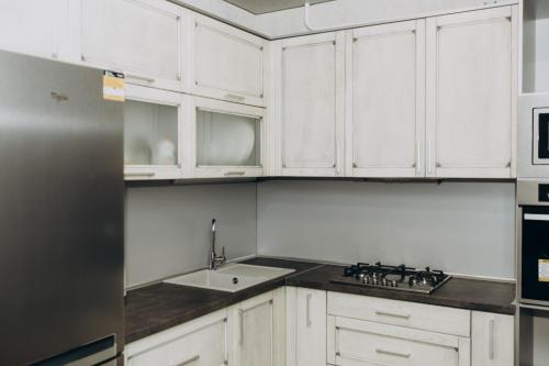 a kitchen with white cabinets and a sink and a refrigerator at Greatest Luxury Apartment in Sumy