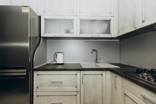 a kitchen with white cabinets and a stainless steel refrigerator at Greatest Luxury Apartment in Sumy