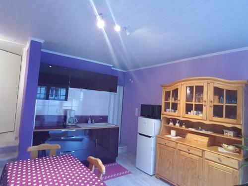 a kitchen with purple walls and a kitchen with a table at La belle endormie - appartement A in Fénétrange