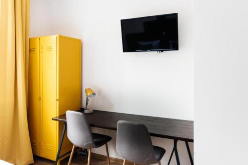 a room with a desk with two chairs and a yellow cabinet at Villa Lulu Piaseczno in Piaseczno